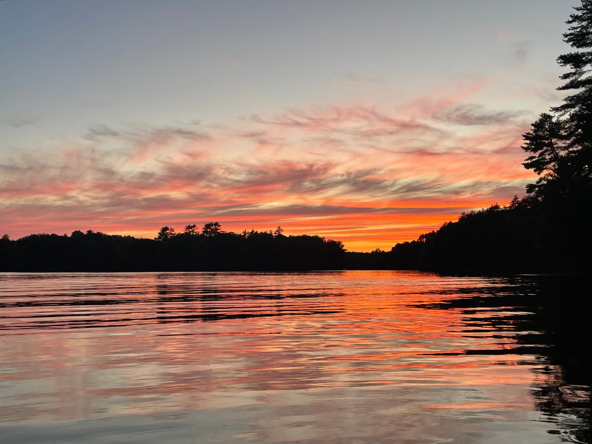 Sunset on Saco River in Maine with trees on the horizon